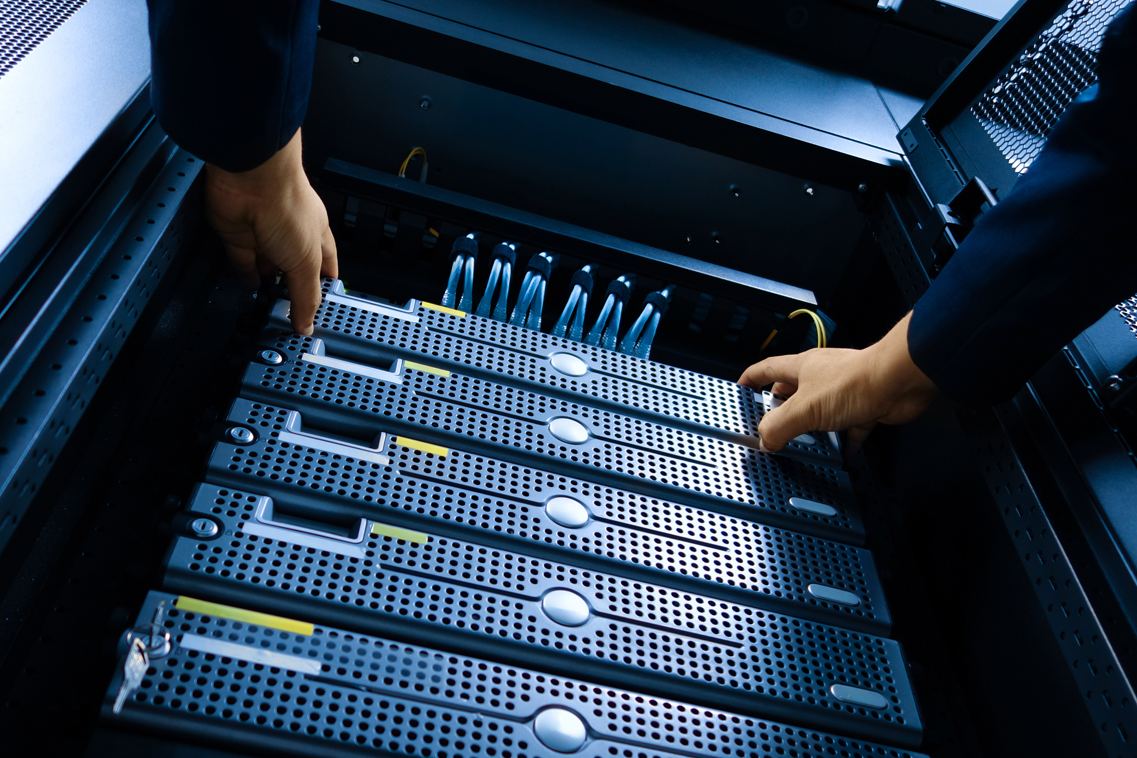 Close-up of hands connecting cabling on network switching equipment.